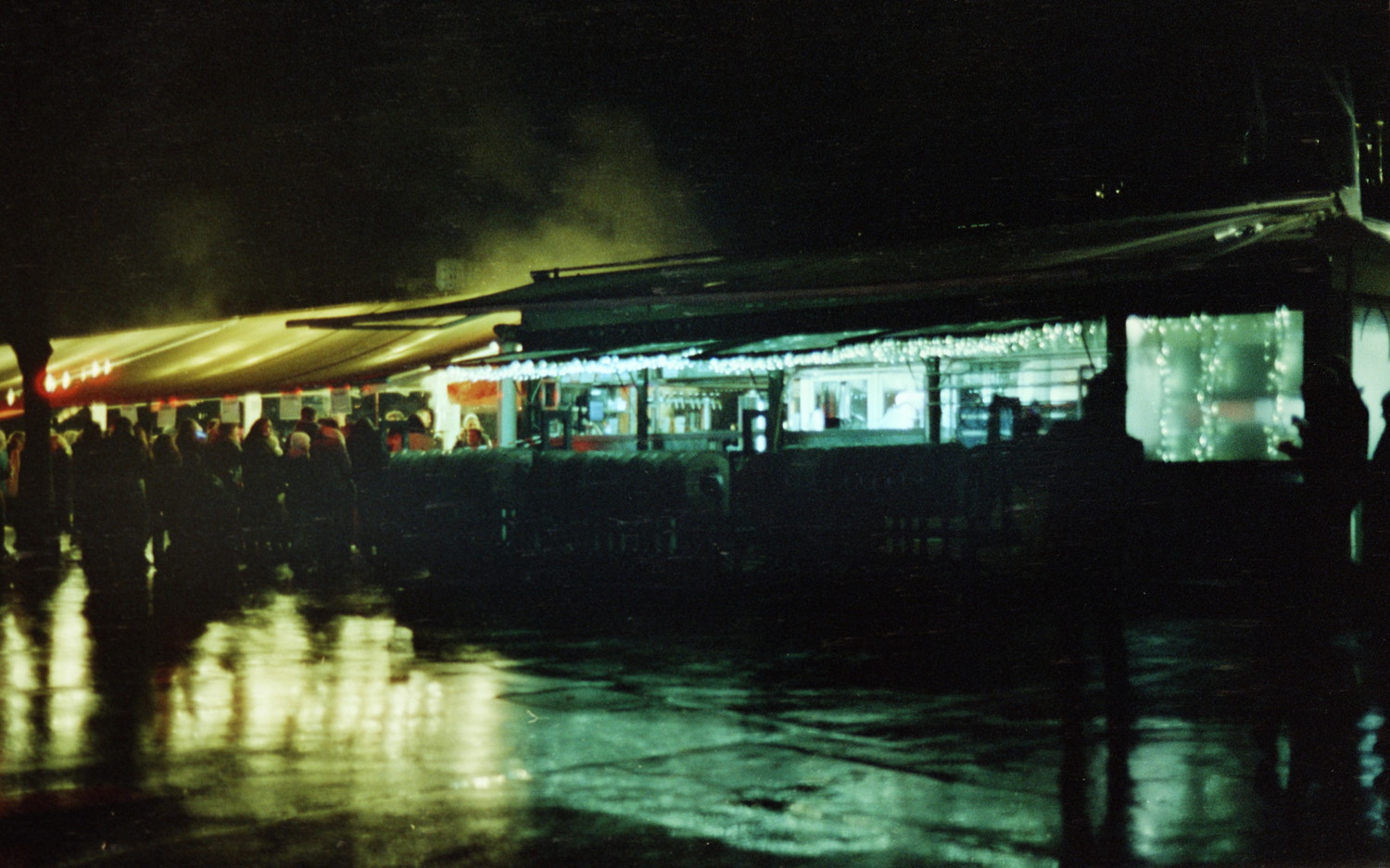 Despite the biting cold of December the mood is festive. It's the light celebration day here in Lyon and people are looking for some warmth at the snack bar installed along the river. The scene is so stunning, where stands' garlands blend between warm and cold splash of lights, creating beautiful reflections in the wet asphalt.