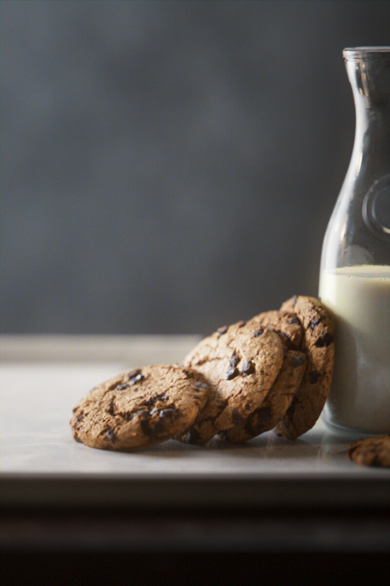 Some cookies against a milk bottle but it looks like the most intentional advertisment possible with perfect lighting and unaturally placed cookies.
